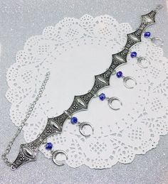 Victorian Gothic metal choker with crescent moon charms and blue crystal beads, ornate metal necklace, Victorian jewelry, Gothic jewelry A beautifully ornate gothic silver metal choker with Victorian crescent moon charms and blue faceted crystal beads. It measures approx. 11 inches in length and has lobster clasp fastening and an extension chain, so that it can be adjusted to fit the neck. The choker is made up of 7 silver toned metal ancient style sections that have intricate detailing. A marve Gothic Blue Metal Jewelry, Crescent Metal Jewelry For Festivals, Metal Crescent Jewelry For Festivals, Blue Gothic Metal Jewelry, Metal Crescent Shaped Festival Jewelry, Crescent-shaped Metal Jewelry For Festivals, Blue Festival Jewelry With Moon Charm, Festival Blue Jewelry With Moon Charm, Festival Jewelry With Blue Moon Charm