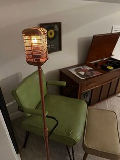 a floor lamp sitting on top of a metal pole in a living room next to a green chair