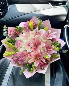 a bouquet of flowers sitting on top of a car seat next to a steering wheel