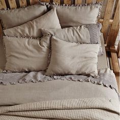 a bed with four pillows on top of it and a blanket over the headboard