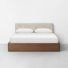 a bed with two pillows on top of it and a wooden frame in the middle