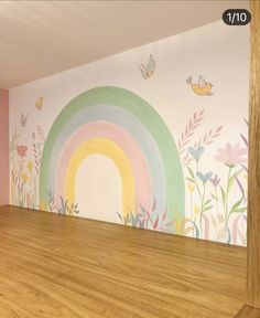 an empty room with a rainbow painted on the wall and birds flying over it, in front of a wooden floor