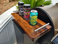 an outdoor bbq with two cans of beer on it and a can opener next to it