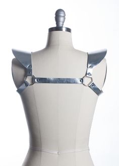 This chestpiece shoulder harness adds drama and impact to any outfit. Epaulette shoulder "wing" details. Show them you mean business! This piece works especially well with dresses and flowing tops that don't have a defined waistline. Silver toned nickel-plated steel hardware. Shown in silver metallic leather (silver leather is now lined and stitched!). Also available in black leather, black vegan leather, and PVC.Buckles in front across chest. All pieces are MADE TO ORDER, standard sizes XS-4XL. Elegant Fitted Black Harness, Gothic Party Harness With Straps, Punk Style Party Harness With Belt, Punk Party Harness With Belt, Fitted Strapped Harness For Party, Elegant Black Party Harness, Edgy Belt Harness For Night Out, Edgy Harness With Belt For Night Out, Gothic Fitted Harness For Party