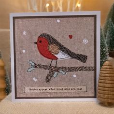 a card with a red bird sitting on a branch in front of some christmas trees