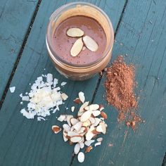 a glass filled with chocolate and almonds on top of a wooden table next to other ingredients