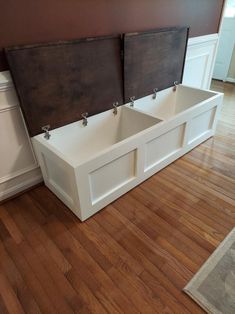 two white benches sitting on top of a hard wood floor next to a brown wall