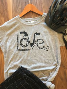 If you love biking or cycling, you will LOVE this fun T-shirt to ride around in or just show off your passion running errands around town. This is a super soft tee which comes in a variety of colors to choose from. The abstract LOVE image is made up of trees, gears, handle bars, and chains with a little heart to top it off. Made in Colorado where bikers enjoy the views!! Graphic Tee T-shirt With Crew Neck For Cycling, Graphic Cycling T-shirt With Crew Neck, Graphic Tee With Crew Neck For Cycling, Short Sleeve Cycling T-shirt With Letter Print, Sporty Graphic Print T-shirt For Cycling, Casual Cotton T-shirt For Cycling, Graphic Print Short Sleeve T-shirt For Cycling, Crew Neck Cotton T-shirt For Cycling, Cotton Crew Neck T-shirt For Cycling