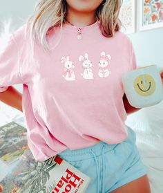 Coquette Bow Easter Bunny t-shirt. These tees are Comfort Colors and are made to last using premium ringspun cotton, this creates an vintage-soft shirt. The soft-washed, garment-dyed fabric brings extra coziness to your wardrobe while the relaxed fit makes it an excellent daily choice. ✦ 100% Ringspun Cotton ✦ Relaxed fit ✦ Medium fabric ✦ Sewn-in twill label ✦ Eco-friendly, Ethically Made & Sweatshop Free ✦ Printed to order with non-toxic ink ✦ Durable and Long-lasting ✦ Shirts are pre-shrunk b Spring Casual Shirt With Cartoon Print, Spring Cartoon Print Relaxed Fit Shirt, Kawaii Crew Neck Top With Letter Print, Cute Cartoon Print Crew Neck T-shirt, Spring Kawaii Letter Print Tops, Cute Crew Neck T-shirt With Cartoon Print, Cute Short Sleeve Relaxed Fit Tops, Cute Relaxed Fit Short Sleeve Tops, Spring Kawaii T-shirt With Funny Print