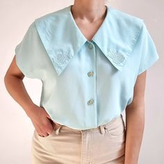 Gorgeous vintage blouse in aqua blue with beautiful chelsea collar. It has short dolman sleeves, floral collar embellishment and five round buttons. It is made from a lightweight and smooth polyester fabric. Perfect blouse for everyday or special occasions. Made by C&A. 100% polyester. Labelled as size 16 UK, 40, would Medium to Large size. Measurements when laid flat are: Pit to pit: 52cm Waist: 50cm Hemline: 54cm Length: 61cm. Excellent condition. B. Light Blue Short Sleeve Button Blouse, Light Blue Short Sleeve Blouse With Buttons, Spring Tops With Peter Pan Collar And Buttons, Daywear Tops With Peter Pan Collar And Buttons, Spring Peter Pan Collar Top With Buttons, Peter Pan Collar Tops With Buttons For Spring, Spring Blouse With Embellished Collar, Peter Pan Collar Top For Daywear, Light Blue Fitted Top With Collar