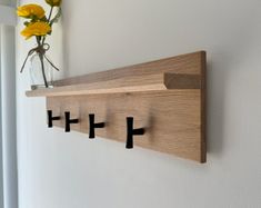 a wooden shelf with three black crosses on it and flowers in a vase behind it