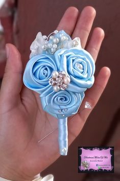 a hand holding a blue flower with pearls on it