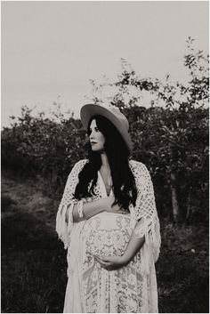 black and white photograph of a woman with long hair wearing a dress, hat and shawl