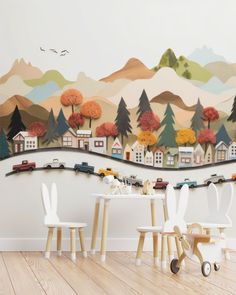 a child's room with a wall mural and toy cars on the table in front of it