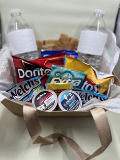 a box filled with different types of snacks and drinks on top of a white table