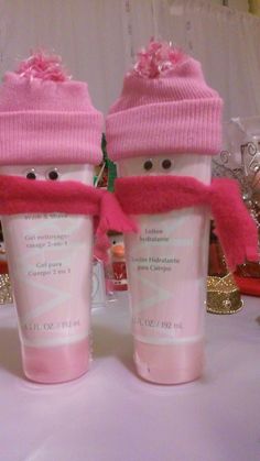 two frosty cups with pink hats and scarves on them sitting on a table