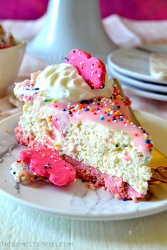 a slice of cake with sprinkles and pink frosting on a plate