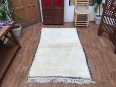 a living room with wooden floors and white rugs on the floor next to a chair