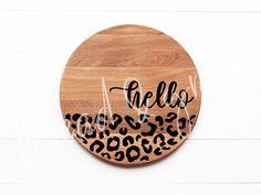 a wooden plaque with the word hello written in black ink and a leopard print on it