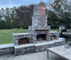 an outdoor fireplace with patio furniture and lights on the top, in front of a golf cart