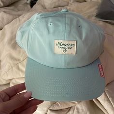 a blue hat with the words masters tournament on it is held up by someone's hand