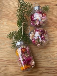 three glass ornaments with flowers in them on a wooden table