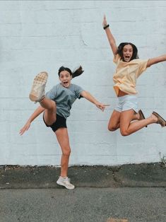 two girls jumping in the air with their arms outstretched