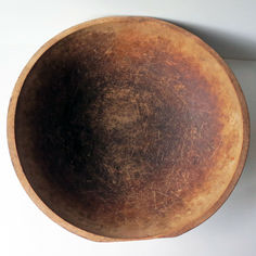 an old wooden bowl sitting on top of a white wall