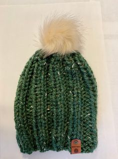 a green hat with a white fur pom