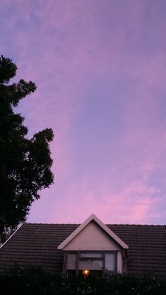 the roof of a house with a tree in front of it at sunset or dawn