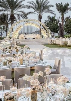 an outdoor dining area with tables and chairs set up for a formal function in front of palm trees