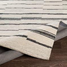 an area rug with grey and white stripes on the floor, next to a wooden floor