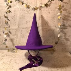 UPDATE: AUGUST 2023- These hats are now made with two layers of felt in the cone.  The double layer makes for a stronger hat which stands up on its own while still being light enough to be comfortable. Looking for a fun witch hat?  Who says that witches have to wear black?  Want to look like you stepped out of the pages of a fairy tale?  Searching for a unique hat for Halloween?  This is perfect for the practical witch who wants her hat to stay put while she soars through the night sky on her broomstick. These witch hats are made out of soft amethyst purple wool/rayon felt.  Satin ribbons tie under your chin.  Choose from a classic straight cone or a whimsical, crooked cone.   Wool Felt is a blend of 35% wool and 65% rayon.  It's a very soft, flexible fabric which makes a lightweight, comf Curved Brim Costume Hat, Costume Hat With Curved Brim, Adjustable Flat Brim Costume Hat, Adjustable Felt Hat For Parties, Adjustable Felt Top Hat For Winter, Adjustable Felt Hat For Party, Adjustable Brimmed Mini Hats In Felt, Adjustable Felt Party Hat, Fitted Brimmed Halloween Hat