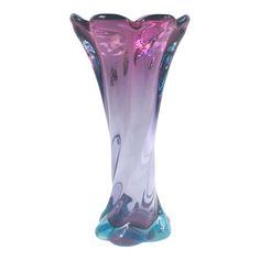 a purple and blue glass vase sitting on top of a white table next to a wall