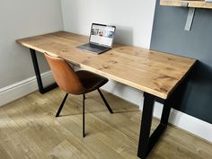 a laptop computer sitting on top of a wooden desk next to a brown leather chair