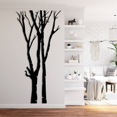 a living room with white walls and wooden flooring, two black trees on the wall