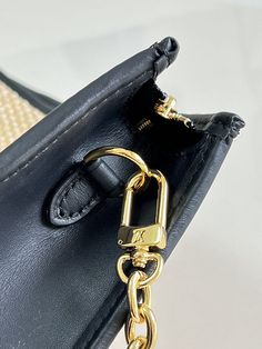 a black handbag with a gold chain hanging from it's front pocket, on a white surface