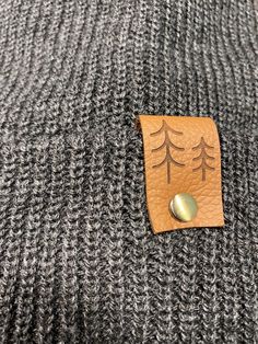 Give the gift of warmth and style! This knit beanie is perfect for hiking, camping, and perfect for keeping warm! Beanie is a dark charcoal gray color, and is made of a soft wool/acrylic blend. Attached is an engraved leather label tag with a brass rivet. The leather label is engraved on both sides, so whether you wear the hat with the brim up or down, the label will still show the design in the correct orientation. Choice of circle logo or trees available at checkout. Care - Hand wash, dry flat Gray Beanie For Fall Outdoor Activities, Gray Beanie For Outdoor Fall Activities, Casual Gray Beanie For Outdoor, Gray Warm Beanie For Outdoor, Warm Gray Beanie For Outdoor, Cozy Gray Beanie, Adjustable Beanie For Cold Weather In Fall, Fall Beanie For Outdoor Activities, Warm Beanie For Outdoor Winter Wear