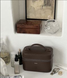 a brown purse sitting on top of a white counter next to bottles and other items