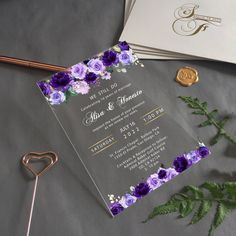 wedding stationery with purple and white flowers on grey fabric next to gold foil stamp