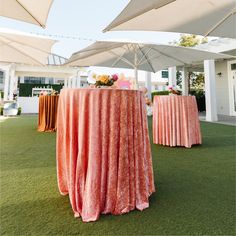 an outdoor event with tables and umbrellas on the grass, set up for a party