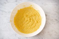 a white bowl filled with yellow powder on top of a marble counter