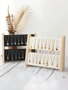 two display racks with necklaces on them next to a potted plant