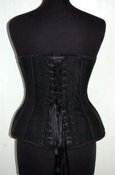 "This is our standard hipgore overbust corset, made in an embroidered raw silk. It's a black on black floral & foliage design. It is also back laced with a matching black double satin quarter inch wide black ribbon and front busk fastening, hand made matching silk bias binding top and bottom to match the boning casings and main body. Comes compete with a loose style modesty panel. The silk is backed with woven vilene, which then has a British herring bone cotton coutil lining. All lovingly c Floral Foliage, Foliage Design, Modesty Panel, Lace Tights, Overbust Corset, Corset Belt, Future Outfit, Bias Binding, Underbust Corset