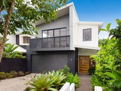 a modern house with trees and plants in the front yard