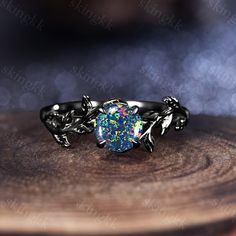 a ring with a blue and white fire opal in the center on top of a wooden