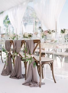 the chairs are decorated with flowers and greenery for an elegant wedding reception in shades of gray