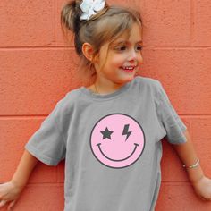 Dress your little one in adorable sweetness with our Pink Happy Face T-shirt.  They will be ready to hit the beach, lake, river or sit by the pool with this tee.   Crafted with care and designed for comfort, this charming shirt is perfect for spreading joy.  Let your Child shine in this shirt that they will love and adore! These t-shirts are mostly Gildan, Bella, Comfort Color or Rabbit Skins. Playful Pink Short Sleeve T-shirt, Playful Crew Neck T-shirt For Playtime, Cute Letter Print T-shirt For Playtime, Pink Short Sleeve T-shirt For Playtime, Fun Cotton T-shirt With Smiley Face, Playful Cotton T-shirt With Cute Design, Playful Crew Neck T-shirt With Cute Design, Cute Pink T-shirt With Funny Print, Cute Pink Crew Neck T-shirt