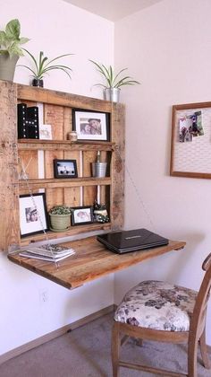 a wooden desk topped with a laptop computer next to a wall mounted book shelf filled with pictures