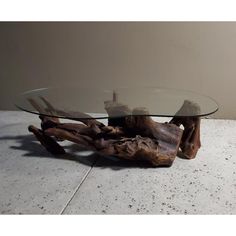 a table made out of driftwood with glass top and wooden base on the floor